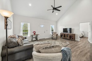 A spacious living room with a sofa, armchair, and a television. - Lookout Retreat  Near Chattanooga (Trenton)