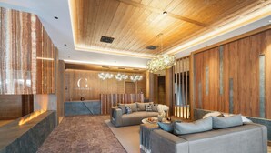 A modern lobby with a sofa, a reception desk, and a chandelier. - Guerneres Resort & Spa (Grimentz)