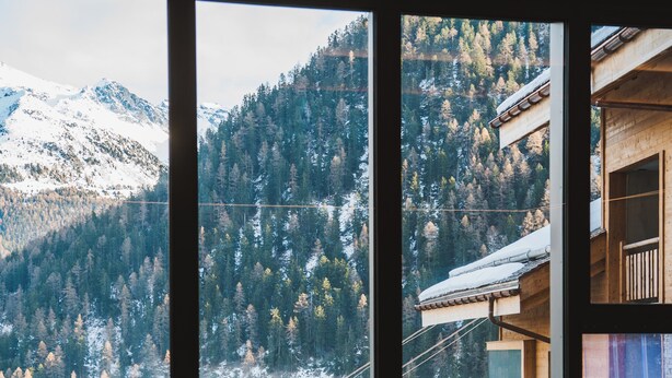 A room with a large window overlooking a snowy mountain landscape. - Guerneres Resort & Spa (Grimentz)