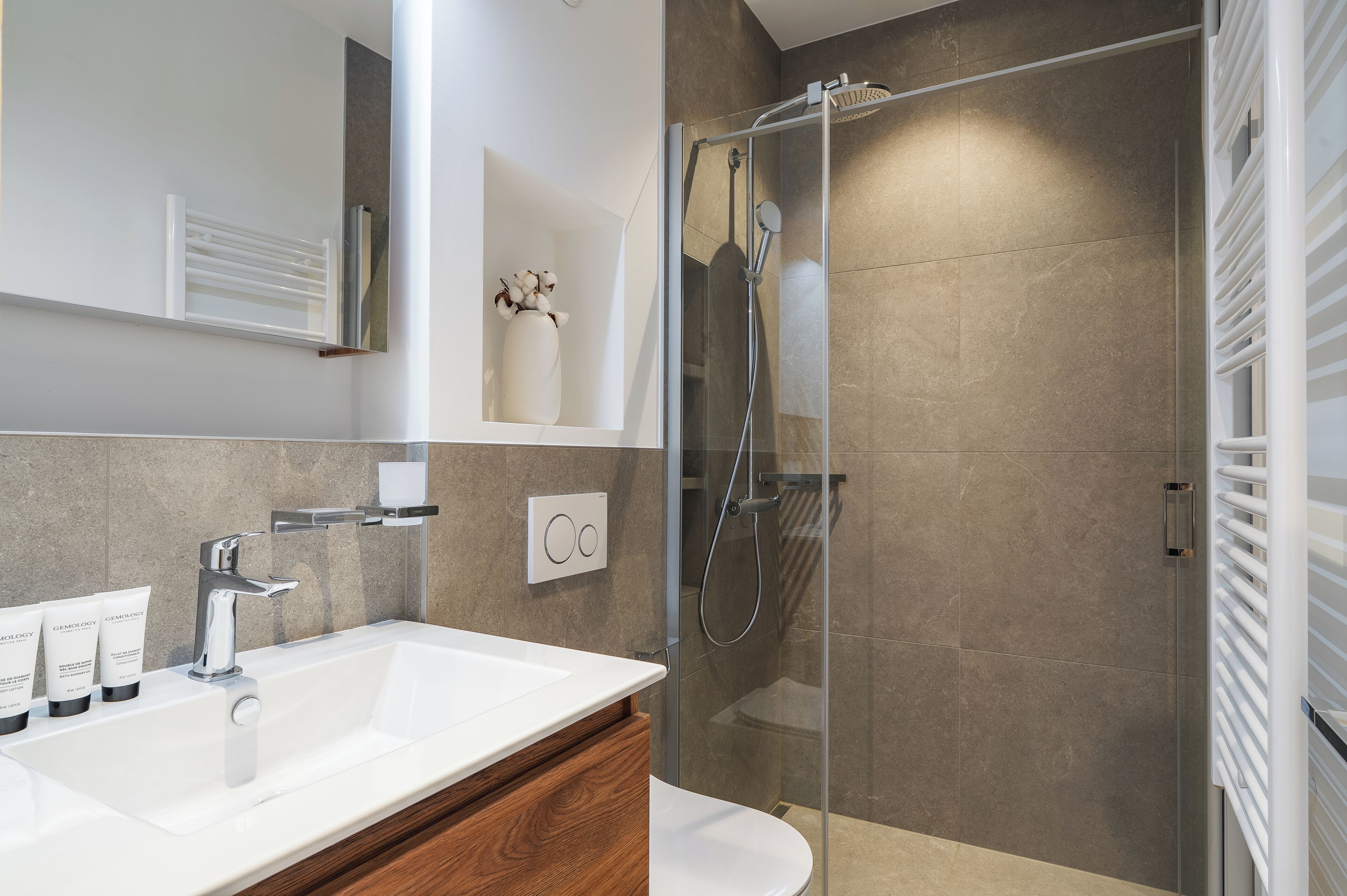 A modern bathroom with a glass-enclosed shower, a white sink, and a mirror.