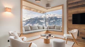 A modern living room with a large window overlooking a snowy mountain.