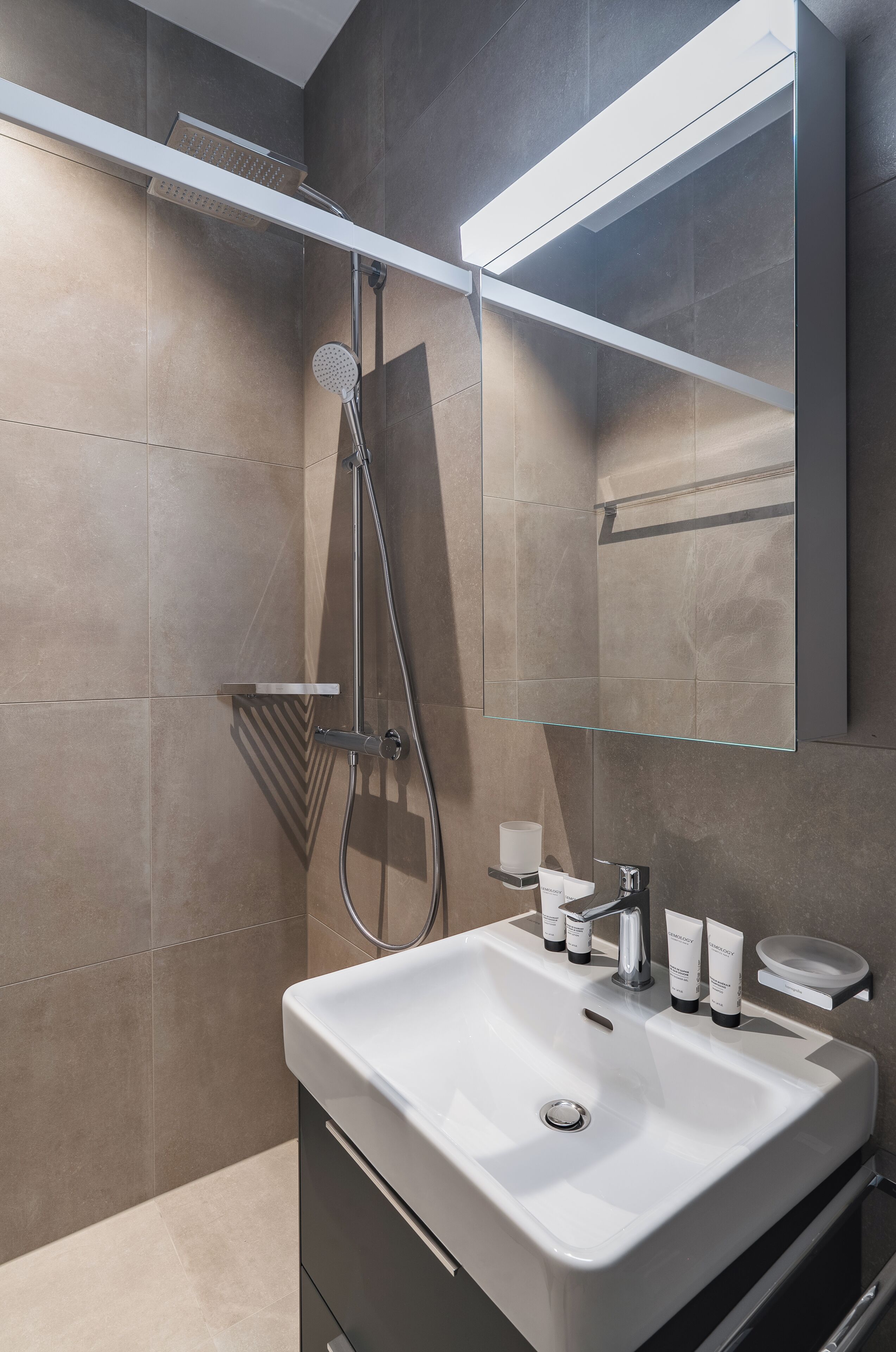 Een moderne badkamer met douche, wastafel en spiegel.