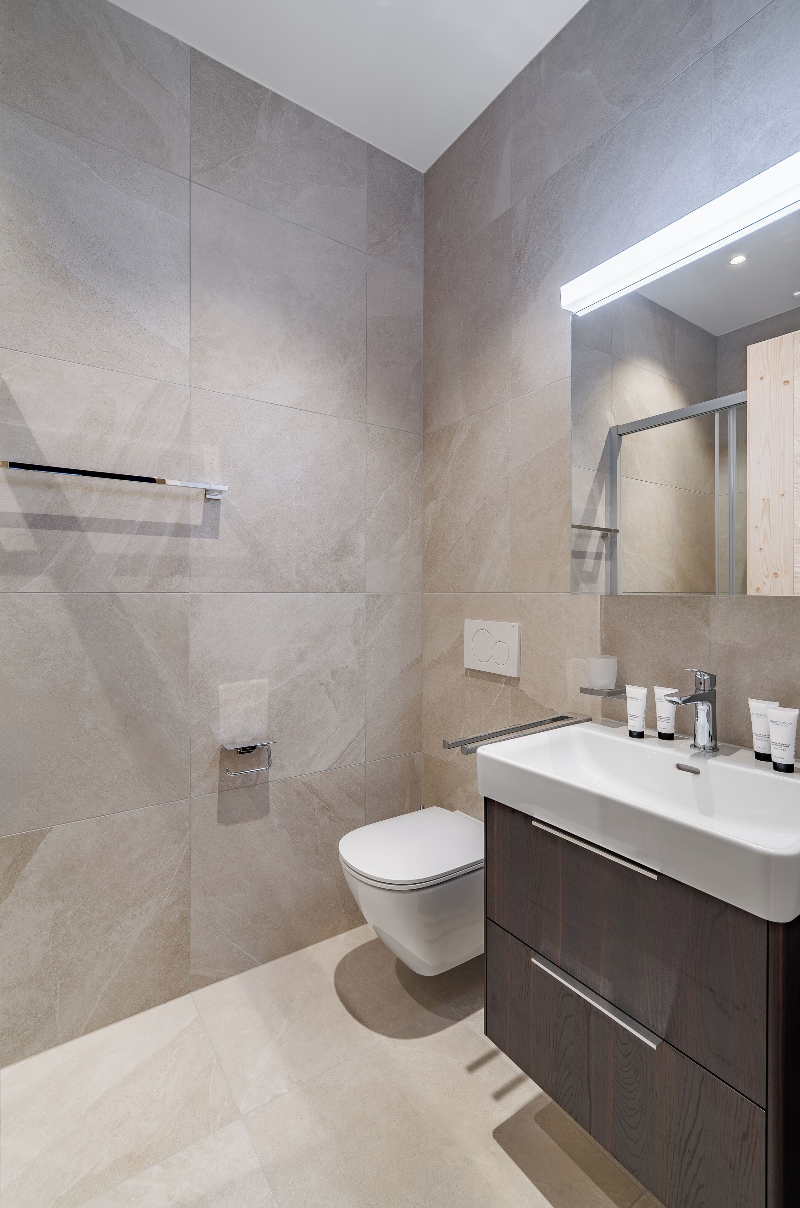 Une salle de bain moderne avec des toilettes, un lavabo et un miroir.