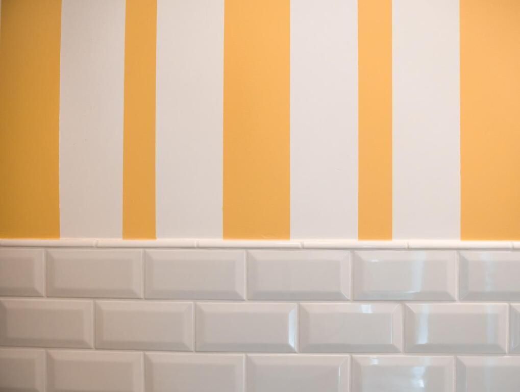 Une salle de bain avec des carreaux rayés blancs et jaunes.
