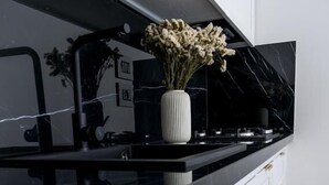 A modern kitchen with a black countertop, white cabinets, and gold handles. - Villa Aurelia (Locorotondo)