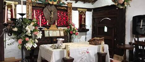 A church interior with wooden pews, a central altar, and floral decorations.