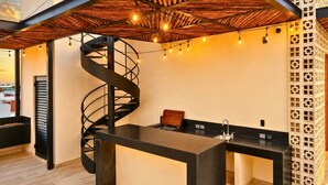 Un interior moderno con una escalera de caracol, una zona de cocina y un muro decorativo.