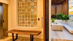 Un interior moderno con un banco de madera, un biombo decorativo y un área de estar con plantas.