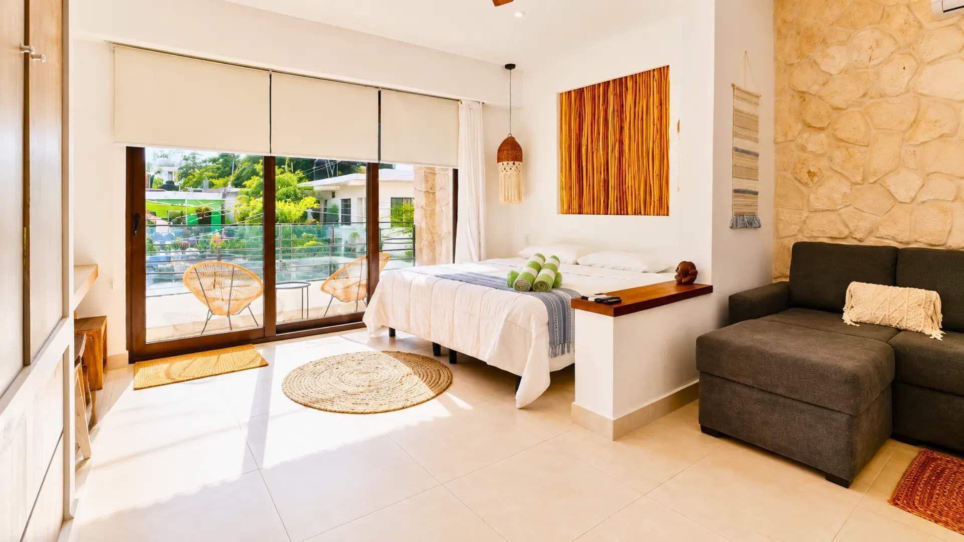 Une chambre moderne avec un lit, un coin salon et une vue sur l’extérieur, accessible par une porte coulissante.