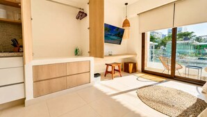 A modern kitchen with a built-in oven, a dining area with a round table, and a large window offering a view of the city. - Bright Balcony Studio Beach Vibe · Blanko Living (Playa del Carmen)