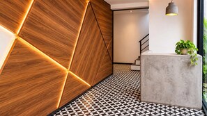 Ein modernes Interieur mit einem geometrisch gemusterten Boden, einem Empfangstresen und einer Treppe.