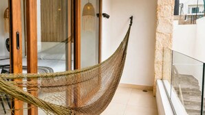 A hammock in a room with a glass door, a bed, and a hanging light fixture. - Cozy Studio steps from Coco Beach · Blanko Living (Playa del Carmen)