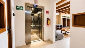 An elevator with a sign indicating the evacuation route, a fire extinguisher, and a wooden ceiling structure. - Cozy Studio steps from Coco Beach · Blanko Living (Playa del Carmen)