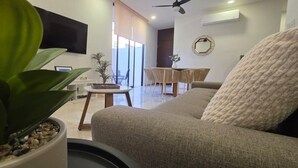 Un salon avec un canapé, une table basse, un téléviseur et une plante en pot.