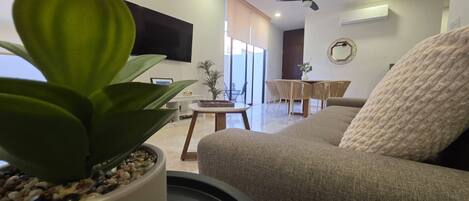 A living room with a sofa, a coffee table, a TV, and a potted plant.