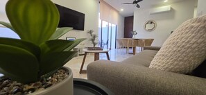 Ein Wohnzimmer mit einer Couch, einem Couchtisch, einem Fernseher und einer Topfpflanze.