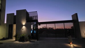Un bâtiment moderne doté d’une entrée sécurisée par un portail, d’un extincteur et d’une personne se tenant près du portail.