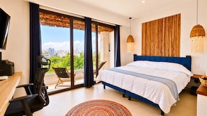 Ein Schlafzimmer mit einem großen Bett, einem Schreibtisch mit Stuhl, einem Fernseher und Blick auf Grün durch die Fenster.
