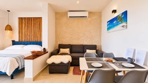Ein modernes Hotelzimmer mit Bett, Sofa, Esstisch und Klimaanlage.