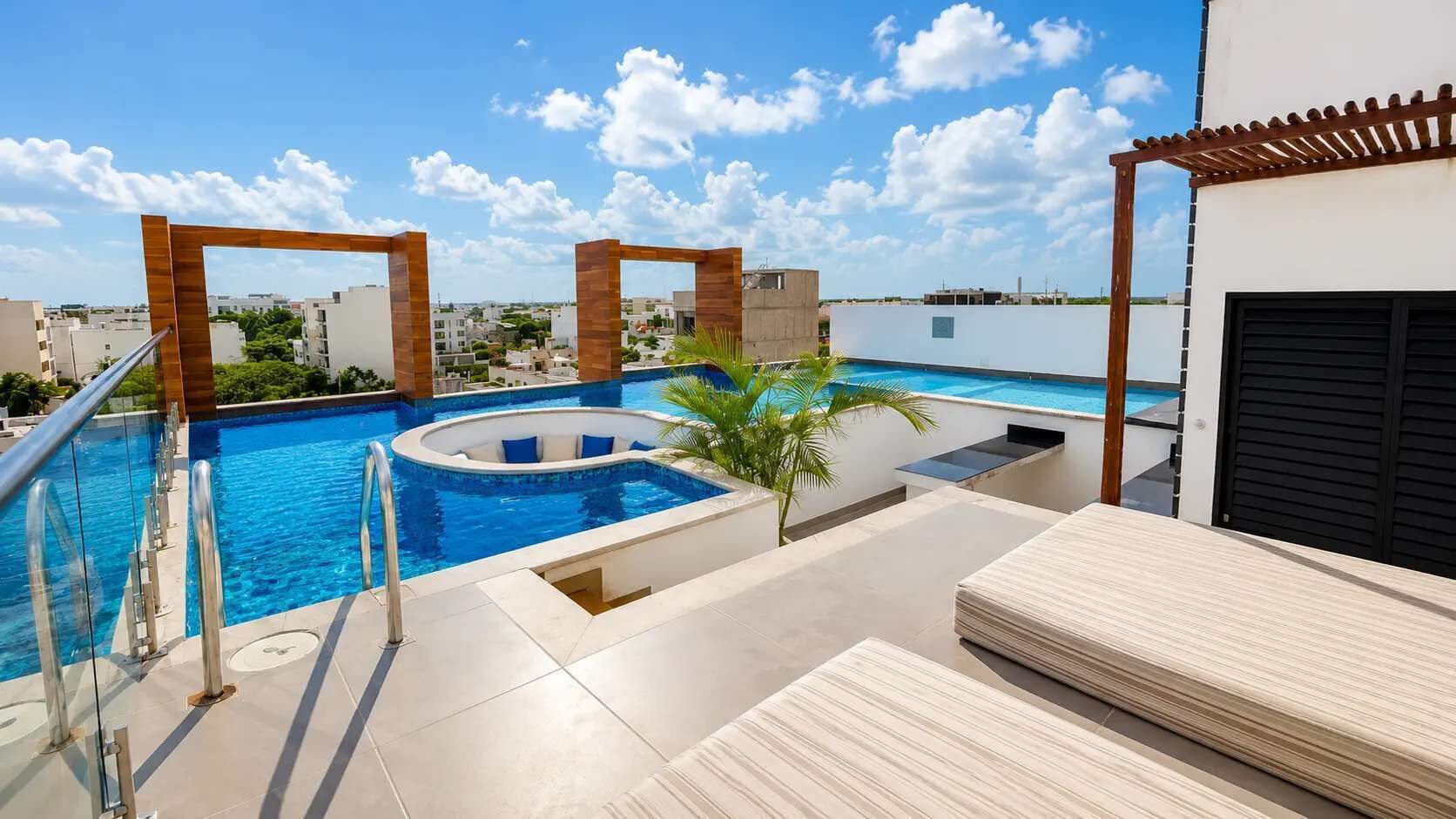 Una piscina en la azotea con barandilla de cristal, un jacuzzi y una pérgola.