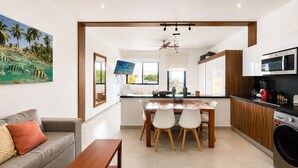 Een moderne keuken met een eethoek, een wasmachine en een groot raam met uitzicht op palmbomen.