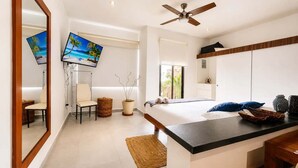 Een moderne slaapkamer met een bed, een televisie, een plafondventilator, een bureau en een raam.