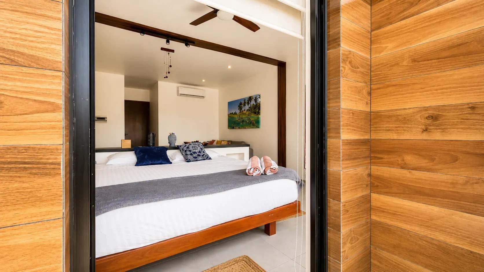 A bedroom with a wooden bed frame, a gray blanket, and a blue pillow.