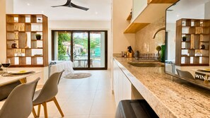 A modern kitchen with a granite countertop, a dining area with a table and chairs, and a large sliding glass door leading to an outdoor space. - Relaxed Studio with  Hammock · Blanko Living (Playa del Carmen)