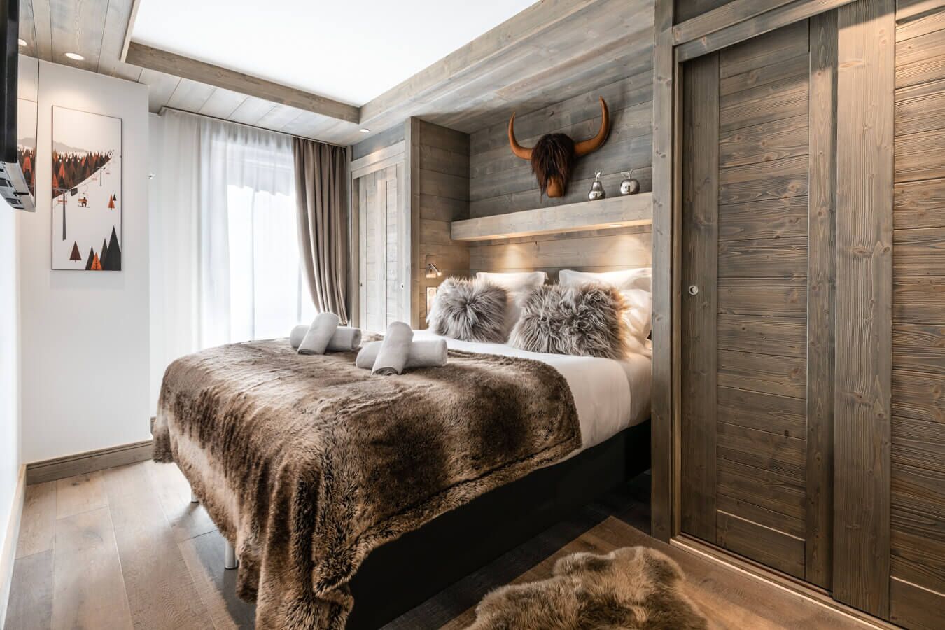 A bedroom with a bed, a wooden headboard, a large horn decoration, and a wardrobe.
