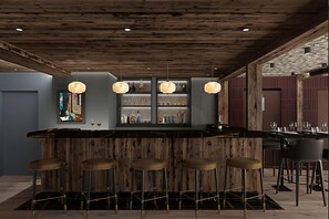 A bar area with wooden bar stools, pendant lighting, and shelves with bottles. - Steamboat by Alpine Resorts (Courchevel)
