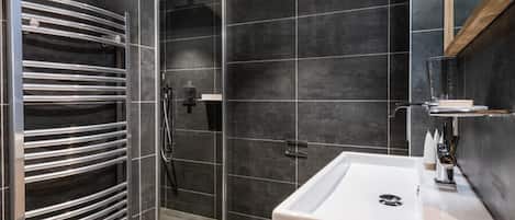 Une salle de bain moderne avec un grand miroir, un lavabo blanc et un porte-serviettes.
