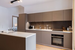 A modern kitchen with a central island, stainless steel appliances, and a minimalist design. - Steamboat by Alpine Resorts (Courchevel)