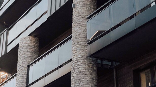 Een meerhoog gebouw met een modern architectonisch ontwerp, met grote glasramen en stenen zuilen.