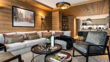 A modern living room with a sofa, coffee table, and a dining area with chairs and a kitchen in the background.