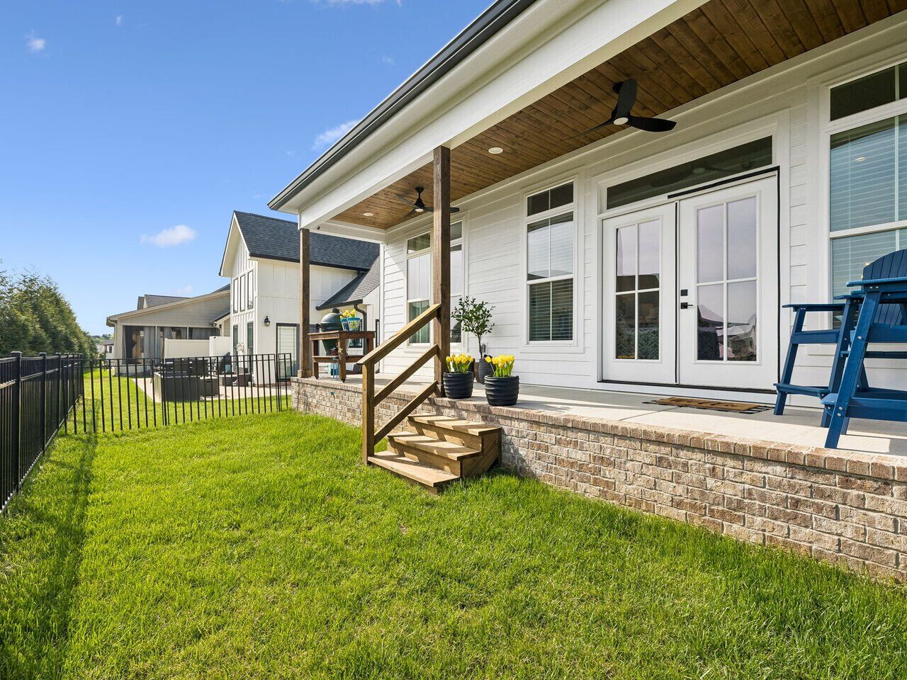 A house with a covered porch, a brick wall, and a wooden staircase leading to the entrance.