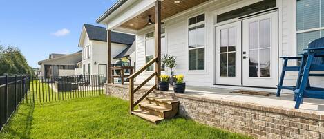 A house with a covered porch, a brick wall, and a wooden staircase leading to the entrance.