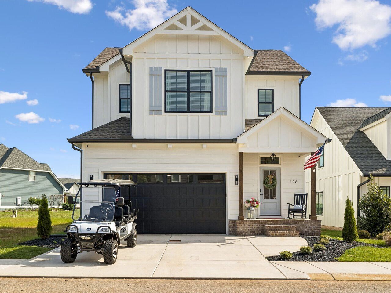 A two-story house with a garage, a driveway, and a golf cart parked in front.