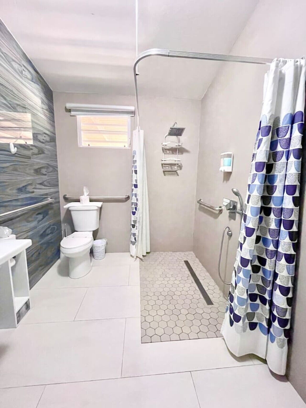 A bathroom with a toilet, shower, and a window.
