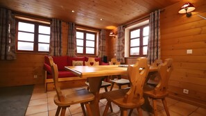 Ein Holzinterieur mit Esstisch, Stühlen, einer Couch und Vorhängen.