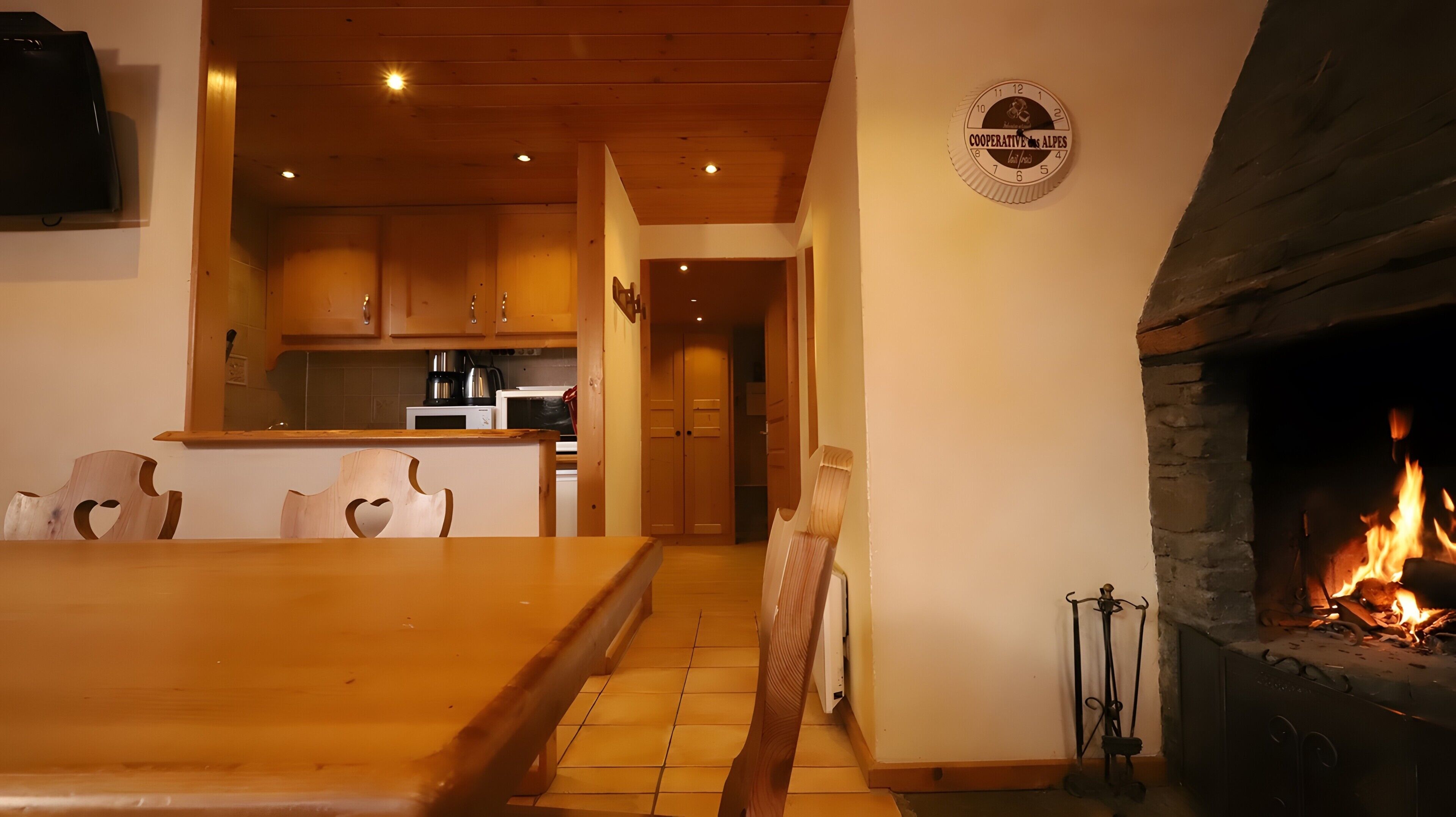 Un ambiente accogliente con un tavolo da pranzo in legno, sedie, angolo cottura e camino acceso.
