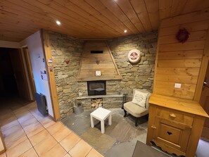 Ein gemütliches Zimmer mit Kamin aus Stein, einem kleinen Tisch, einem Stuhl und einem Holzschrank.