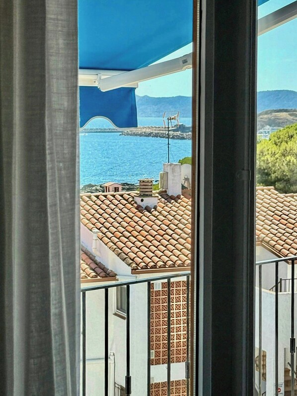 A balcony with a view of a coastal area, including a bridge and buildings with tiled roofs. - Designed Costa Brava apartment with sea views (Girona)