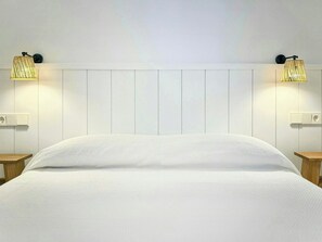 A bed with a white headboard and two wall-mounted lamps on either side. - Designed Costa Brava apartment with sea views (Girona)