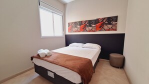 A modern bedroom with a bed, a window, a headboard, and a wall art piece. - LK Centro 5 (Belo Horizonte)