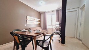 A dining area with a wooden table and chairs, a sofa, and a TV stand with a flat-screen TV. - LK Centro 5 (Belo Horizonte)