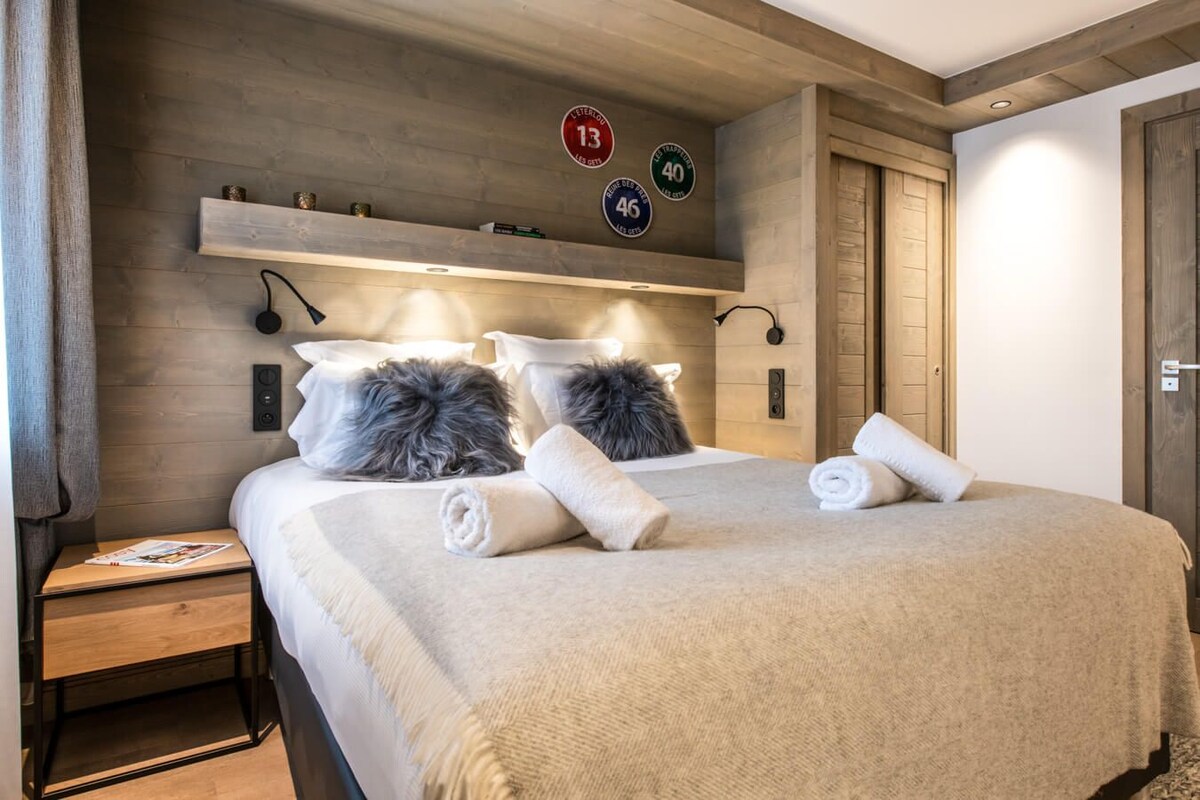 A neatly made bed with pillows, a bedside table with a magazine, and a wall with decorative signs.
