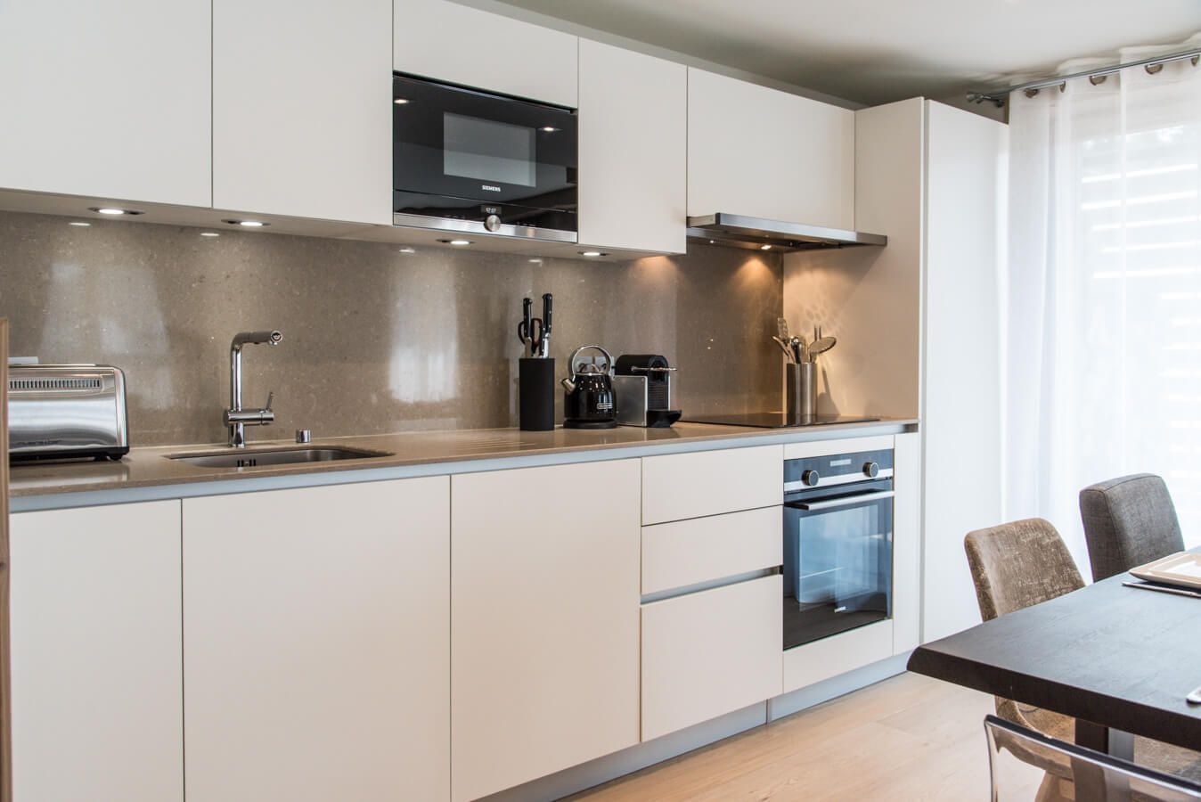 A modern kitchen with a built-in oven, a microwave, and a coffee maker.