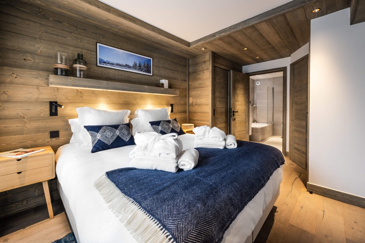 A neatly made bed with white and blue bedding, a wooden headboard, and a framed picture above.