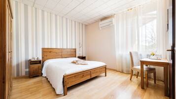 Un dormitorio con una cama de madera, una mesita de noche, una silla, una mesa y una ventana con cortinas.