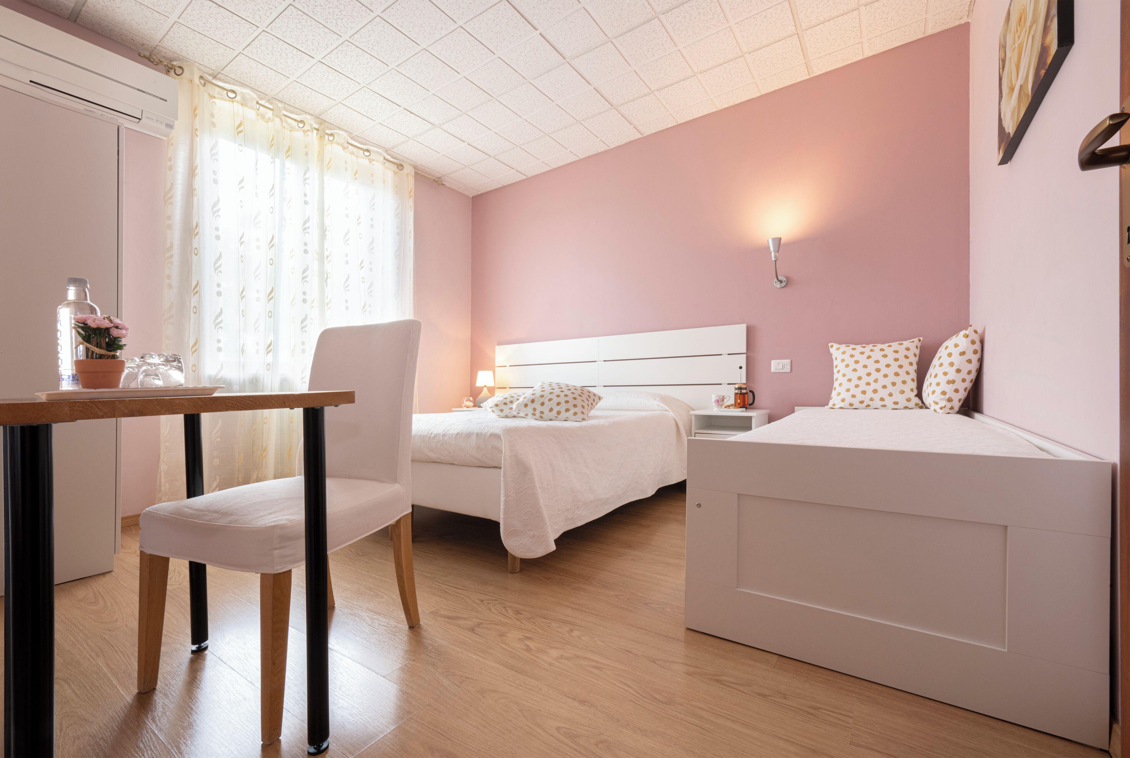 Een slaapkamer met een bed, nachtkastje, lamp en een raam met gordijnen.